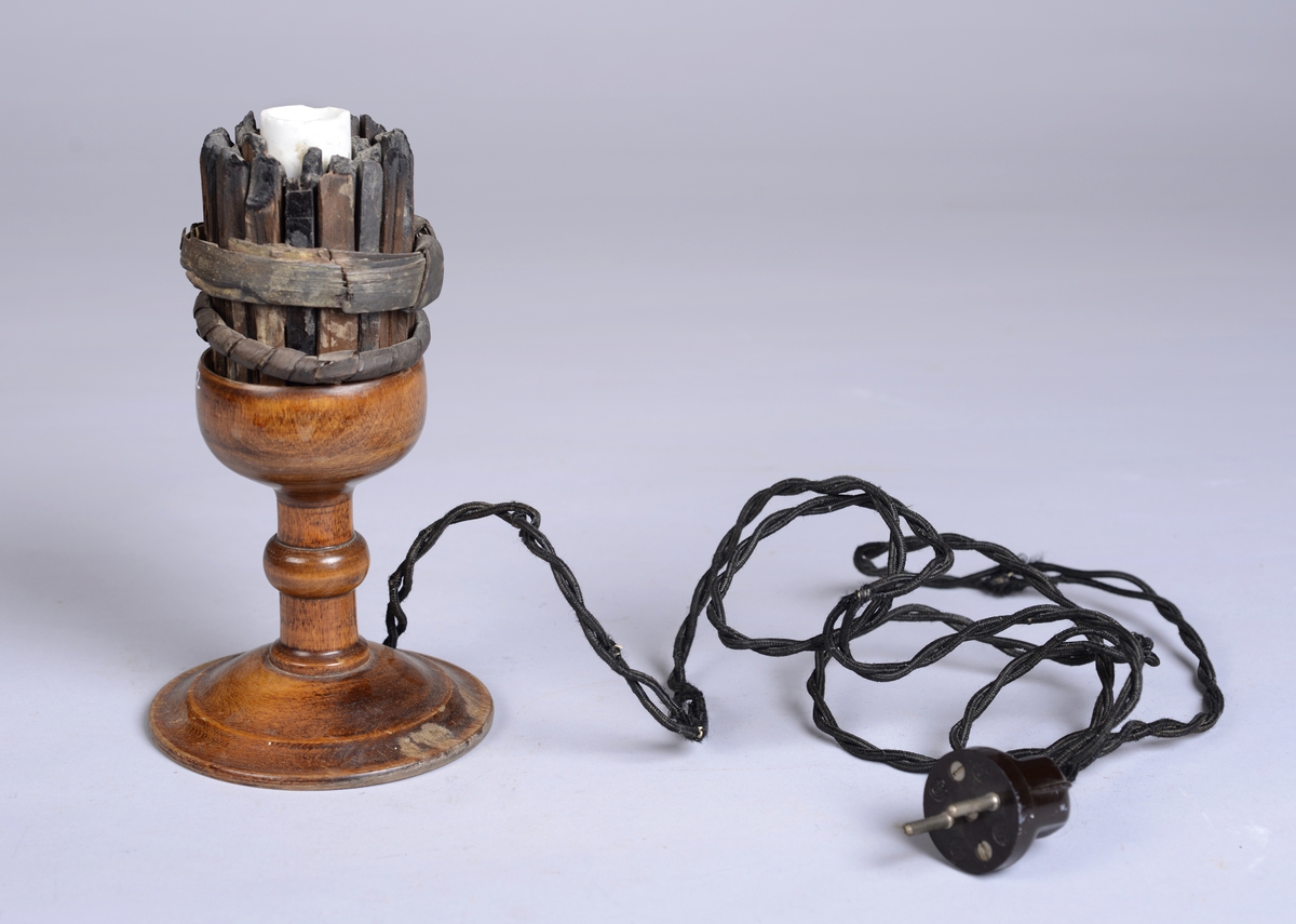 Elektrisk lampe laget av tre og plast. En brukt gruvefakkel av sammensatt tyrispik er brukt som dekorativt element.