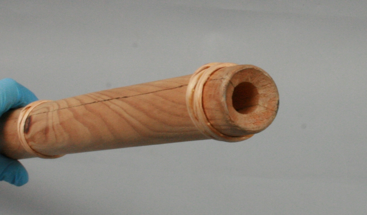 Gjeterhorn, liten lur av tre. Bøyet trestykke delt i to på langs, uthult i halvdeler, limt sammen og forsterket med fem ringer av vidjebånd.
