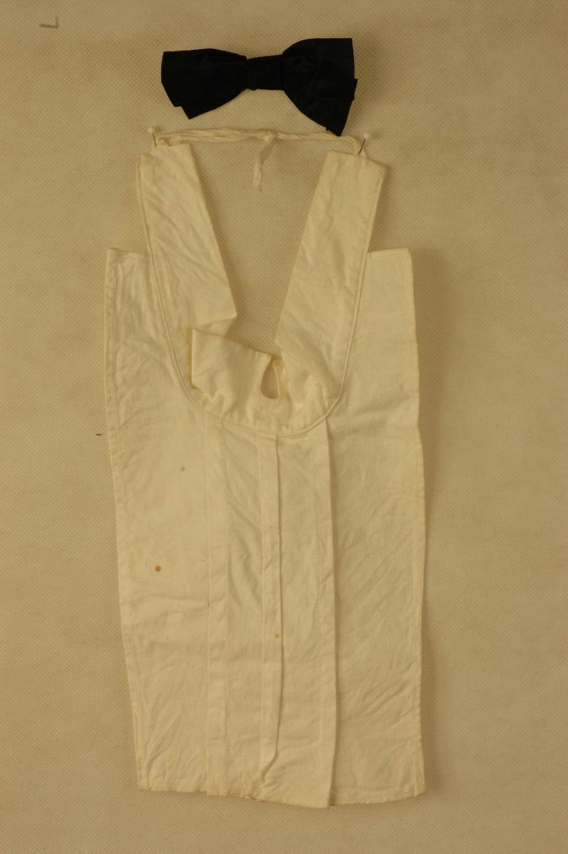 Kvitt skjortebryst i lin med tilhørende løs svart silkesløyfe.