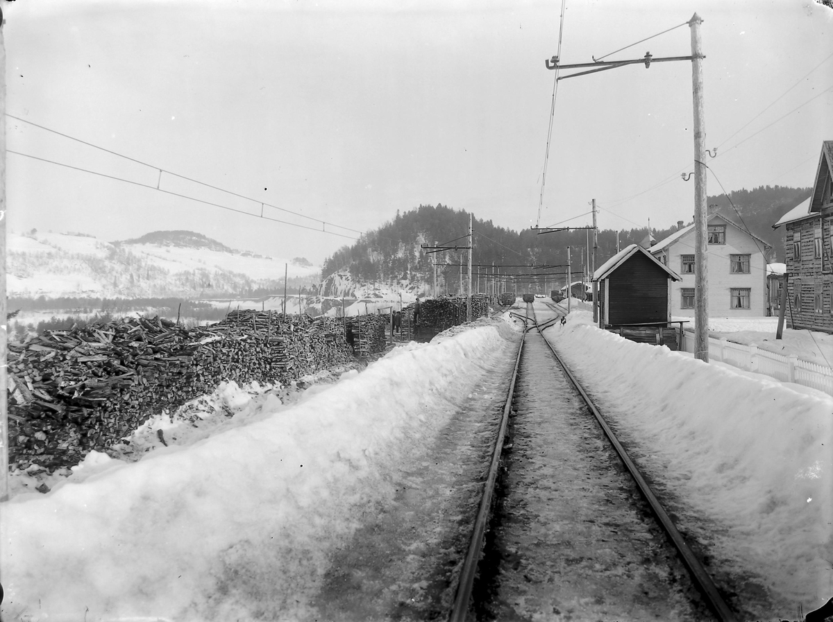 Vinterbilde fra Svorkmo stasjon. Vedopplag ved siden av linja.