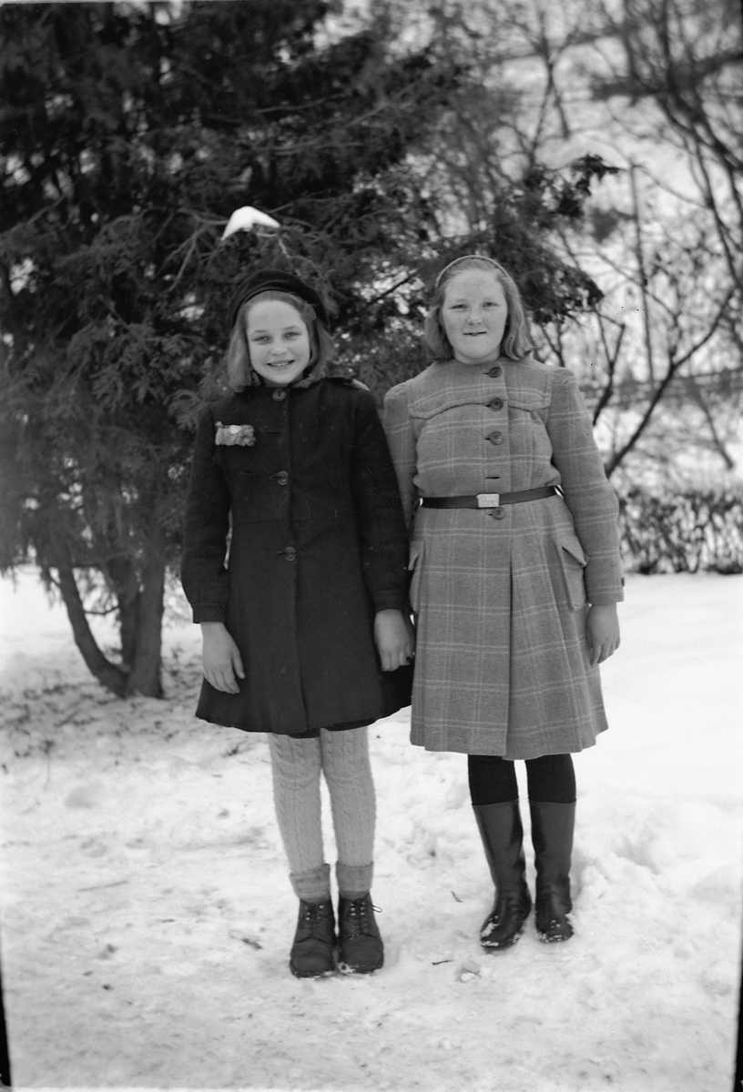 To jenter ved et grantre, vinter. 