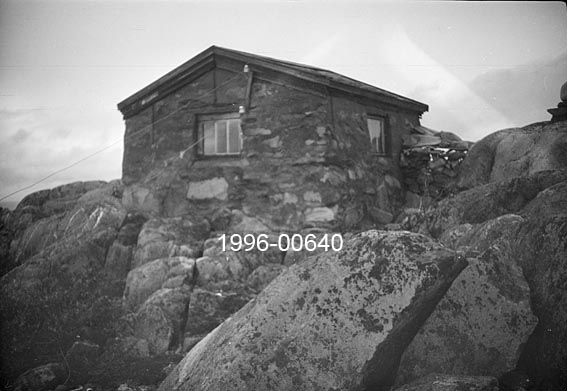 Hytta på Byringen skogbrannvaktstasjon i Ytre Rendalen.  Dette fotografiet viser (i motsetning til SJF. 1996-00639 og SJF. 1996-00641) en murt steinbygning med saltak.  Hytta ligger på berggrunn i et vegetasjonsfattig landskap. 

Byringen ligger øst for Storsjøen, 1 031 meter over havet.  Brannvaktstasjonen her ble bygd av skogeier Simon Sjølie (1885-1938) på Nedre Sjøli i 1904, men seinere overtatt av Ytre Rendal Skogbrannkasse. 

Opptaket er dessverre noe uskarpt.