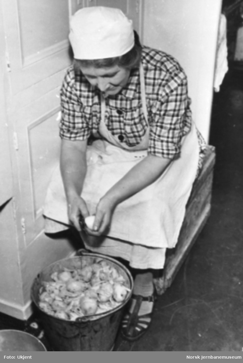 En dame skreller poteter i spisevogn