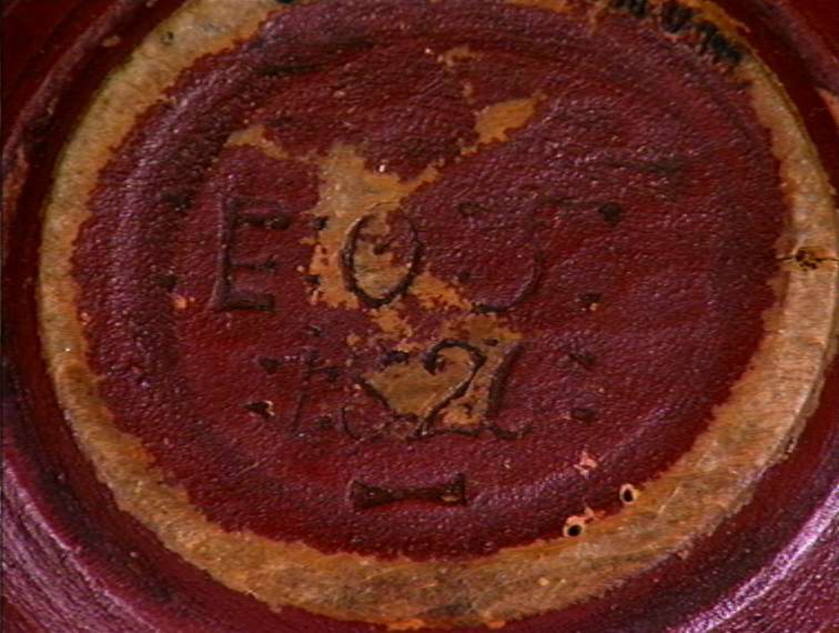 Bjørk, dreiet bolleform med to flate, tungete hanker, utvendig malt rødbrun, innvendig rosemalt på rød bunn. Hankene merket EOSS 1826