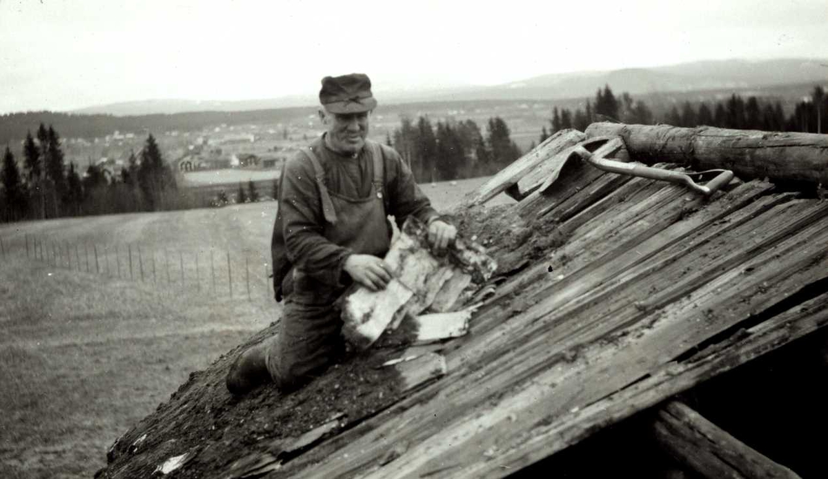 Søndre Murud, Elverum, Sør-Østerdal, Hedmark. Mann arbeider på taket av loft. Spade ligger ved siden av.