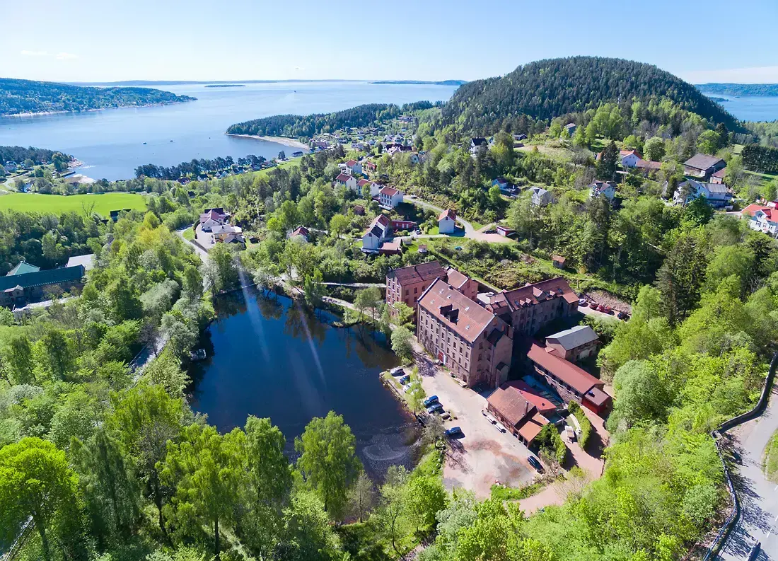 Viser Berger sett ovenifra, med Berger museet og det lille vannet klart og tydelig i forkant av bilde, i bakgrunn ser vi utover fjorden.